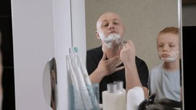 A young father teaches his little son to shave at home in the bathroom in the morning, he shows how to use a razor. - Powered by Shutterstock - Get 15% off with code: PIKWIZARD15