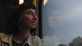woman on a train sits near the window and looks out the window. A woman traveler looks out the train window and enjoys the ride. a train passenger. - Powered by Shutterstock - Get 15% off with code: PIKWIZARD15
