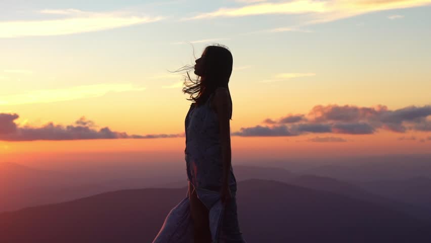 Dreamy girl on sunset. Young woman jump on a summer sky. Peaceful woman alone in a field. Free girl with happiness. Sensual traveler embracing the beauty of life. Freedom and carefree.