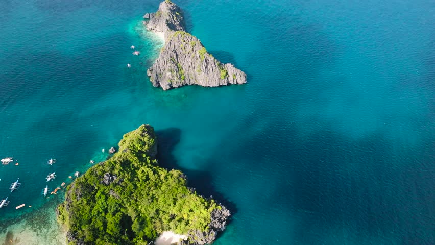 Top view of serene island with coastal cliffs. Boats over the clear water. Twin Rocks in Miniloc Island. El Nido, Philippines.