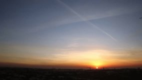 Sunset in the city on a cloudy evening. In the sky, the trail of a flying plane. - Powered by Shutterstock - Get 15% off with code: PIKWIZARD15