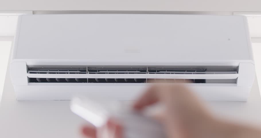 Close up cropped shot of person hand using remote control, adjusting temperature and turning off air conditioning system at home. Comfort in managing indoor climate during changing weather conditions.