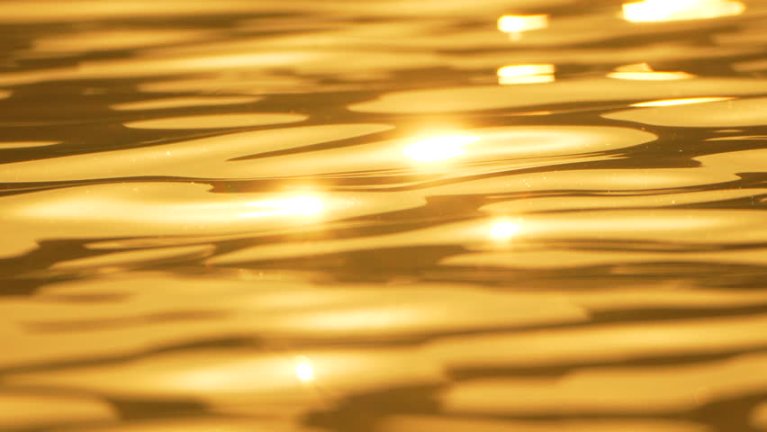 Water Ripples Golden Light Reflections - A close-up of shimmering water with golden light reflections creating ripples on the surface.