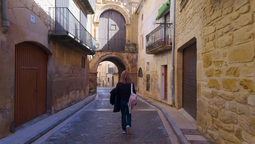 Female tourist on her back strolling through narrow alleys in the medieval village of Calaceite, Teruel, Aragon.