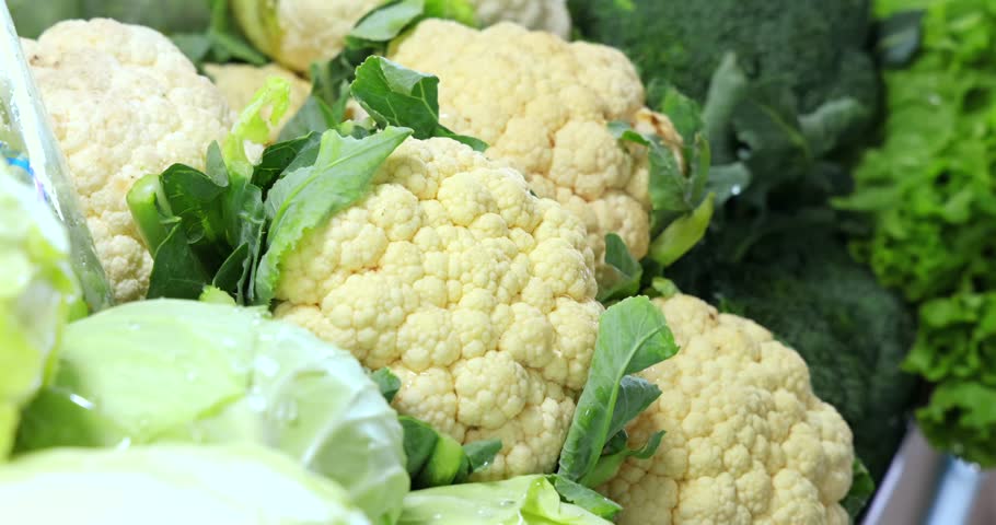 Cauliflower, lettuce, and broccoli displayed at market. Perfect for healthy vegetables, nutrition, cruciferous food, raw ingredients, clean eating.