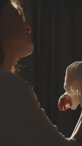 Happy young mother lifting up her newborn baby in slow-motion at home while she is smiling