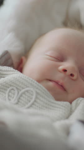 Close-up shot of a baby girl sleeping peacefully in warm clothes at home