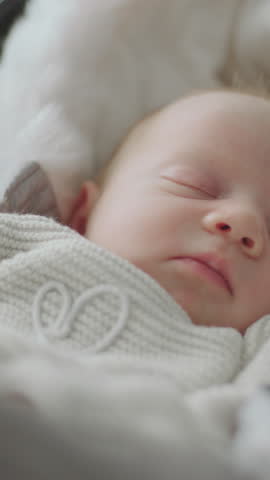 Close-up shot of a baby girl sleeping peacefully in warm clothes at home