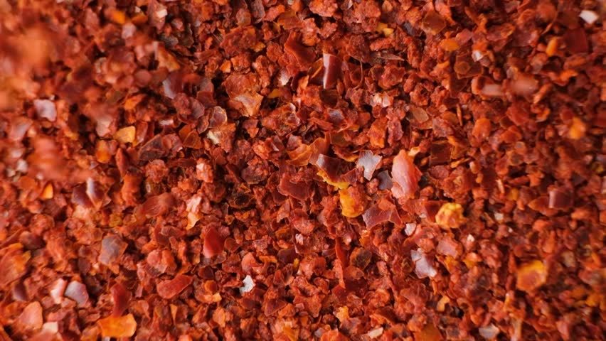 Spicy ground chili pepper pour close-up top view slow motion