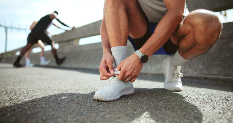 Hands, tie shoe and man with fitness, wellness and prepare with training, outdoor and warm up. Closeup, athlete and runner in city street, practice and workout with sneakers, sports and New York