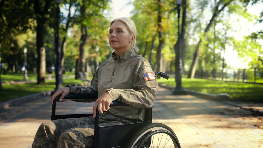 Portrait of American woman soldier in wheelchair enjoying stroll in city park