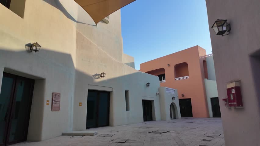 Scenic walk through the colorful buildings of Old Doha Port, Mina District, Qatar, capturing the vibrant architecture and lively atmosphere in the afternoon light.