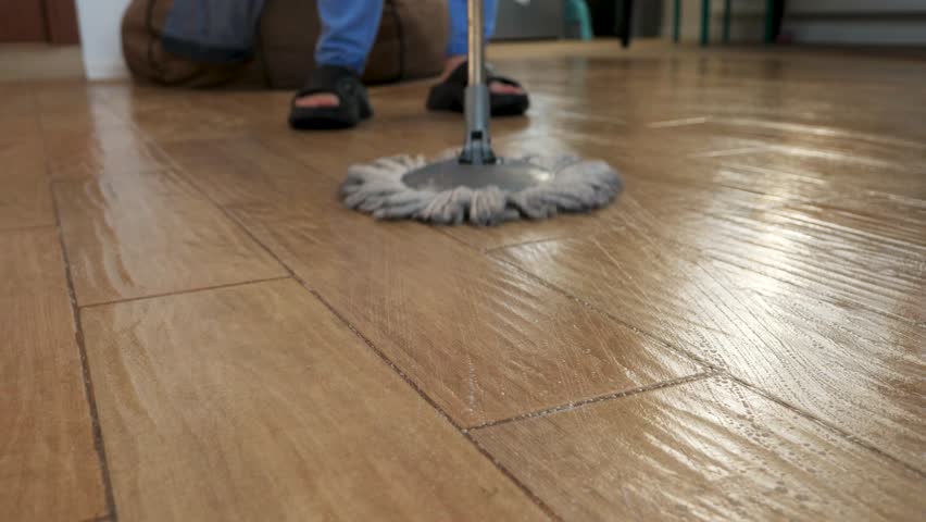 Professional janitor methodically mopping tiled floor, rotating cleaning tool and ensuring spotless, hygienic surface with precise workplace maintenance