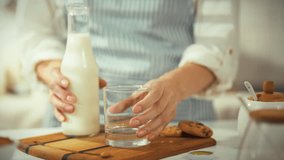 A person is carefully pouring fresh milk into a glass, preparing a delicious snack of cookies. This moment is taking place in a warm kitchen, filled with inviting aromas and a cozy ambiance - Powered by Shutterstock - Get 15% off with code: PIKWIZARD15