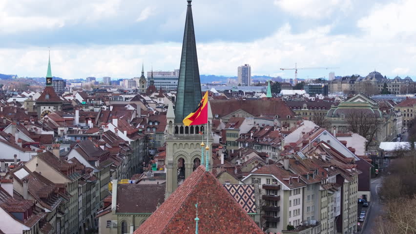 Bernese national flag fluttering above Church of St Peter and Paul, highlighting historic urban landscape of Bern