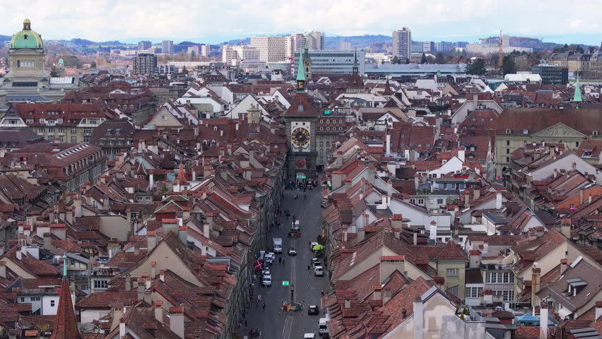 Cityscape of Bern, Switzerland, featuring the Zytglogge astronomical clock tower and red rooftops, seen from an aerial perspective