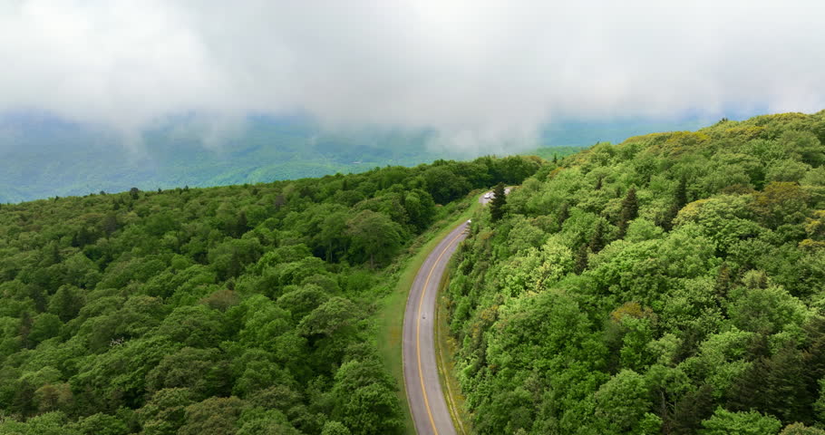 Road trip driving in Tennessee Appalachian mountains. Winding parkway in mountain forest with green canopies in summer rain season