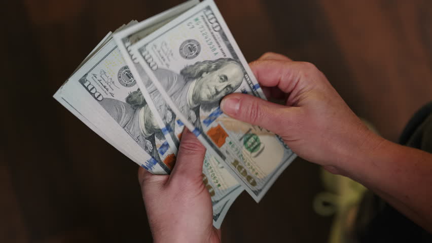Man counting cash money US dollars holding in hands closeup.