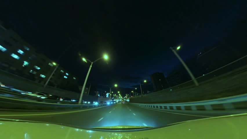 Driving at Night on a Highway, Illuminated by Blurred Street and Car Lights. Hyperlapse Road Trip Travel Concept Sort of Dashcam POV. Concept: Rapid Rhythm of a Modern City