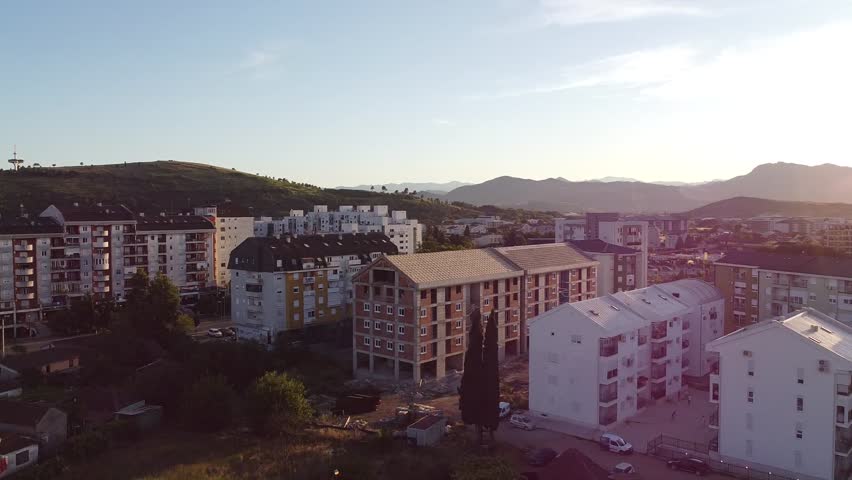 360-degree drone rotation over Podgorica, Montenegro at summer sunset. Warm light, soft shadows, and panoramic views of the Balkan landscape and city blending into golden hour hues