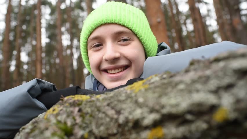 12 year old smiling boy leaning on tree branch