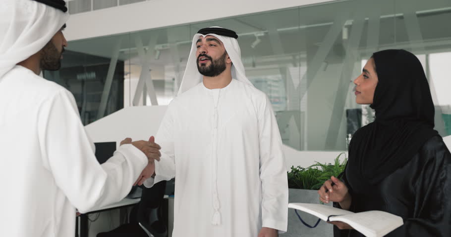 Two Arabic men business partners and woman secretary standing in office, lead formal talk, accomplish meeting, shaking hands, finalize negotiations successfully, thanking each other for cooperation