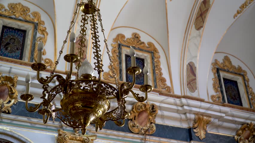 Golden chandelier hanging from the ceiling of a Catholic church.