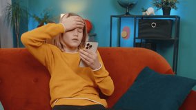 Caucasian Teenager boy checks messages on smartphone at home. Looks sad, receiving bad news in email, negative test results from school, sitting on sofa, showing emotions of disappointment and sadness - Powered by Shutterstock - Get 15% off with code: PIKWIZARD15