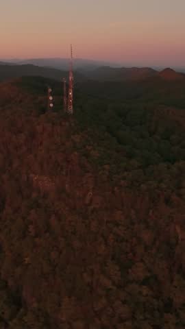 Vertical screen Aerial view of communication towers atop Buffalo Mountain, Tennessee, surrounded by forested hills during golden hour. telecommunication Towers on Buffalo Mountain at Sunset