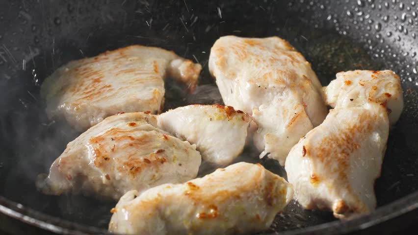 pieces of chicken fillet with spices are fried in a pan in hot oil for a delicious healthy meal, food closeup