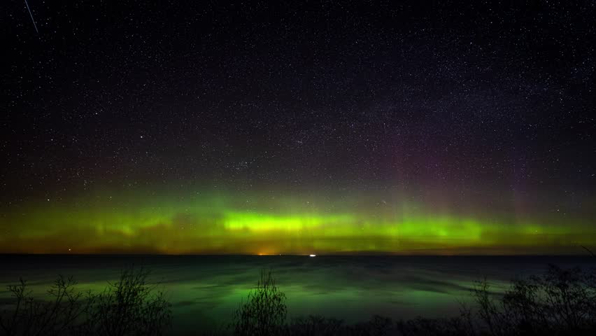 Scenic timelapse. Star trails with the northern lights above the scenic sea.