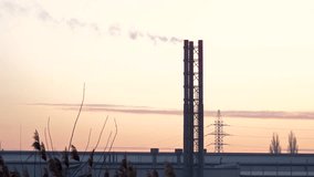 Factory chimneys emit smoke against a colorful sunset while silhouettes of trees and power lines enhance the industrial scene during evening hours - Powered by Shutterstock - Get 15% off with code: PIKWIZARD15