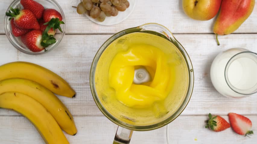 Yellow fruit cocktail mixed in blender. Making organic fruit smoothie using blender. Healthy and healthy drink made by yourself. Vegan drinks and drinkable smoothies for detox. Top view