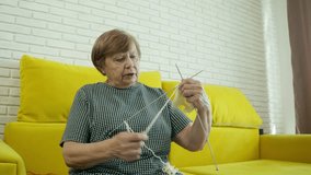 Elderly woman knitting on a yellow sofa - Powered by Shutterstock - Get 15% off with code: PIKWIZARD15