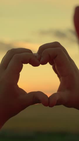 Child boy hands form heart symbol. Child makes heart shape with his fingers against sunset. Child boy plays sun in park, looks through symbol of heart at sky. Family love. Love, Health. Kid dream, Sky