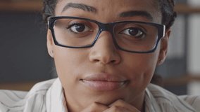 African American woman with glasses contemplates while teaching online, feeling bored. She is a remote educator dedicated to guiding students in their learning journey from her workspace. - Powered by Shutterstock - Get 15% off with code: PIKWIZARD15