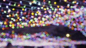 A group of families and friends enjoying a quiet evening in a park decorated with colorful lights to celebrate Christmas - Powered by Shutterstock - Get 15% off with code: PIKWIZARD15