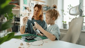 Daughter learns resin jewelry making from her mother home. Carefully selecting colors and pouring epoxy into silicone molds, enjoys crafting handmade accessories. Fun and educational activity kids. - Powered by Shutterstock - Get 15% off with code: PIKWIZARD15