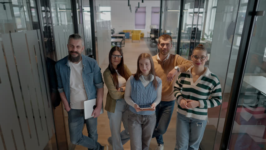 A diverse team of professionals in a modern coworking startup office smiles together, showcasing teamwork, collaboration, and a positive corporate culture that promotes innovation and a dynamic work