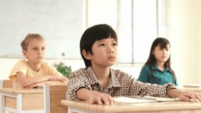 Smart boy raising hand for asking and answering teacher surrounded by multicultural children studying at classroom. Happy student working together, voting, volunteering, calling instructor. Pedagogy. - Powered by Shutterstock - Get 15% off with code: PIKWIZARD15