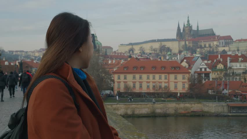 A traveler gazes at the stunning architecture of Prague. The picturesque skyline features historic buildings and the iconic castle in the background, embodying the rich cultural heritage of this beaut