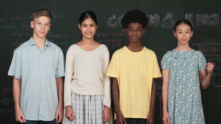 Diverse academic student cheering and celebrate successful project while raised hand. Group of multicultural children standing at blackboard with engineering code while looking at camera. Edification
