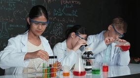 Cute girl looking under microscope while student doing experiment at blackboard with theory written. Young scientist inspect colored solution at table with experimental equipment placed. Edification - Powered by Shutterstock - Get 15% off with code: PIKWIZARD15