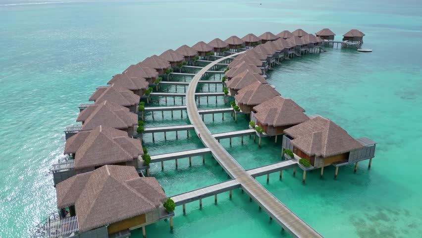 Drone flight over luxury water villas, Maldives. Aerial low flight