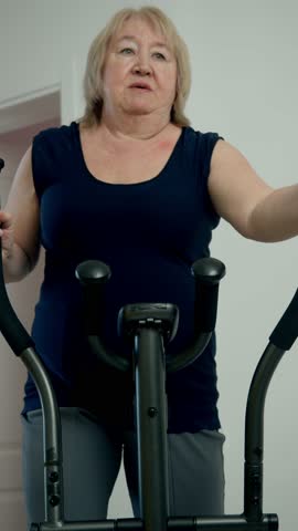 Senior woman exercising on elliptical trainer at home