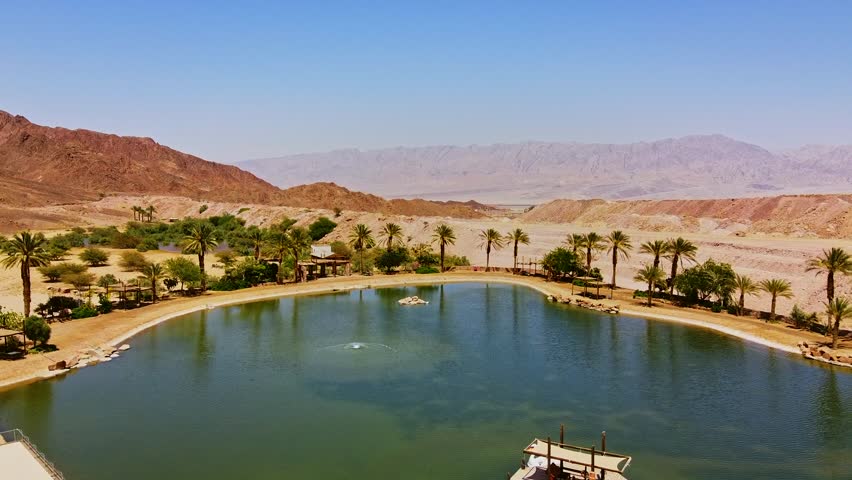 Aerial view of a stunning desert oasis, with turquoise waters contrasting golden sand dunes in Israel.