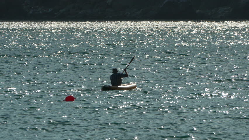 A Man Kayaking on a Sparkling Lake on inflatable kayak