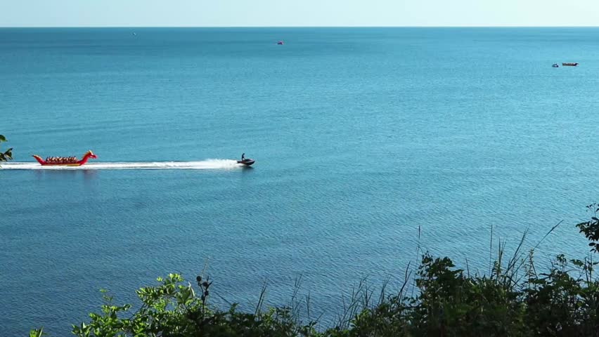 A motor boat carries happy people on an inflatable banana along the Black Sea. Krasnodar region. Vacation, relaxation, entertainment.
