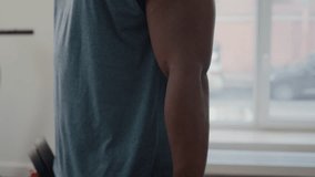 Tilt up shot of strong African American man doing single arm bicep curls with dumbbell during weightlifting workout in home gym - Powered by Shutterstock - Get 15% off with code: PIKWIZARD15