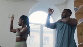 African American couple doing arm mobility exercise together during workout session in home gym with minimalist interior - Powered by Shutterstock - Get 15% off with code: PIKWIZARD15